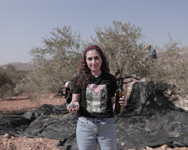 Palestinian farmer from PARC - Al Reef holding olive oil.